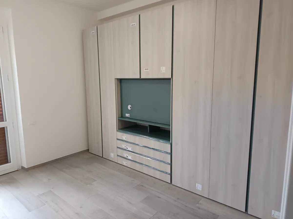 Parete attrezzata su misura in legno chiaro con vano TV e cassetti